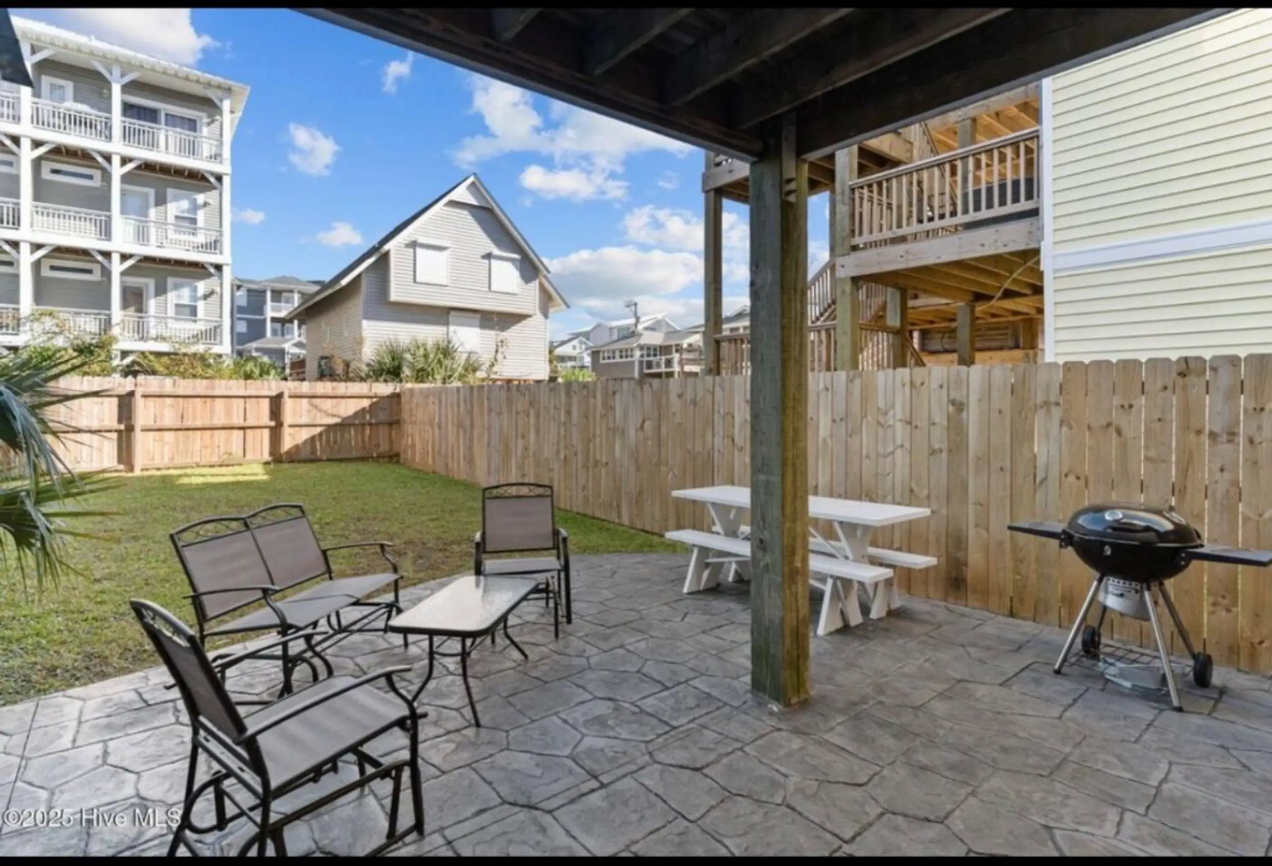Covered patio with chairs, picnic table, grill