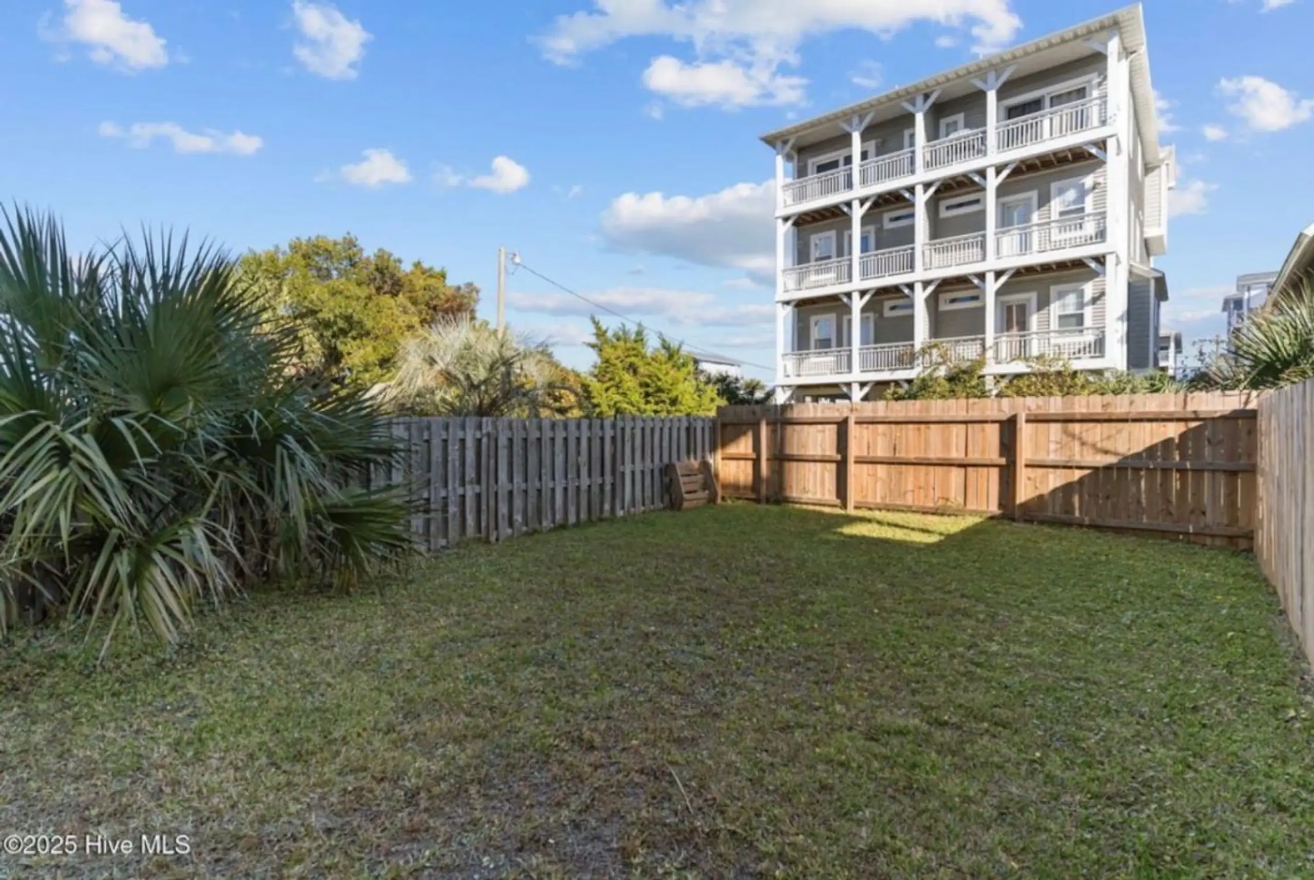 Fenced backyard with multi-story coastal house
