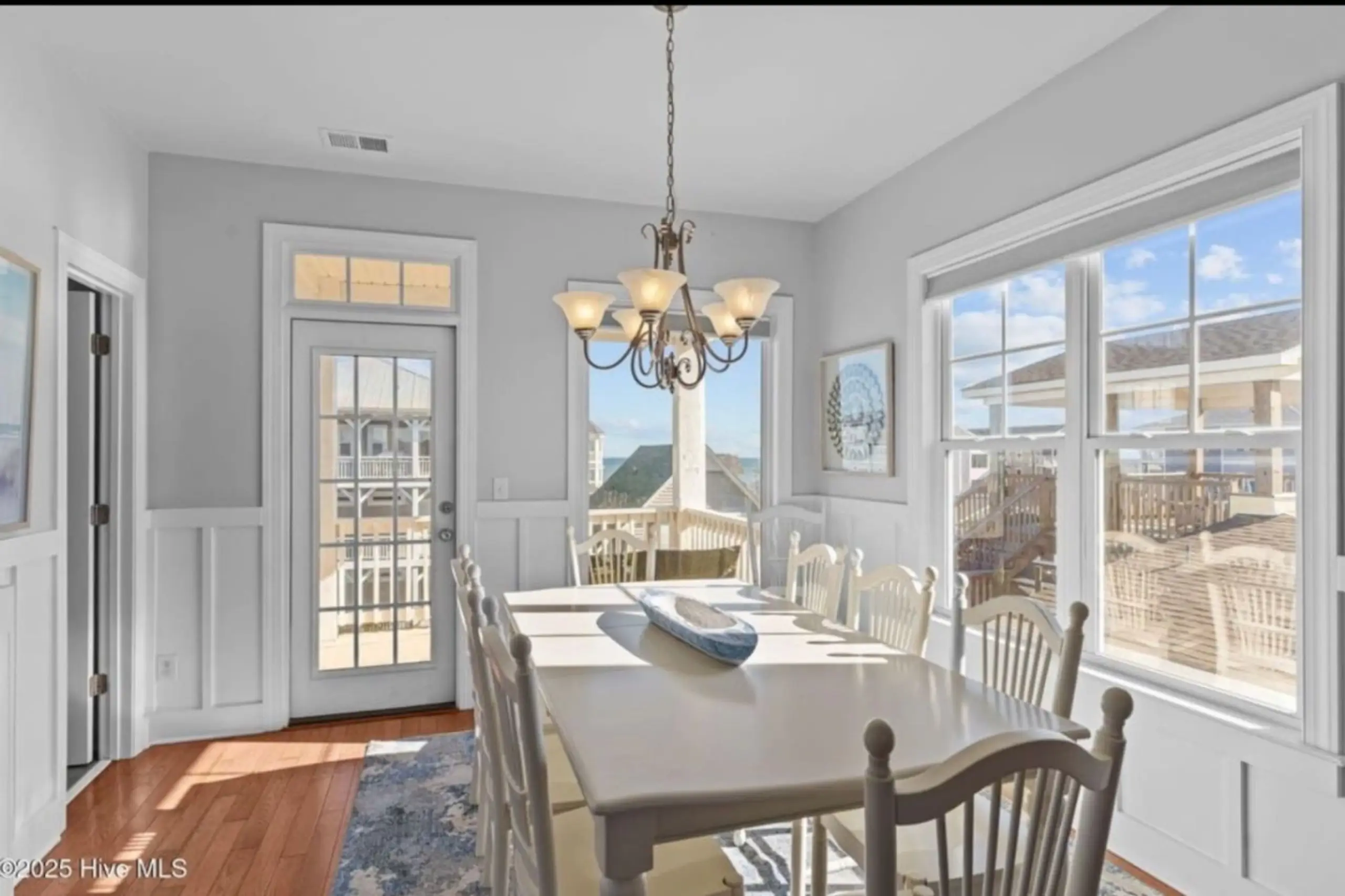 Sunlit coastal dining room with chandelier