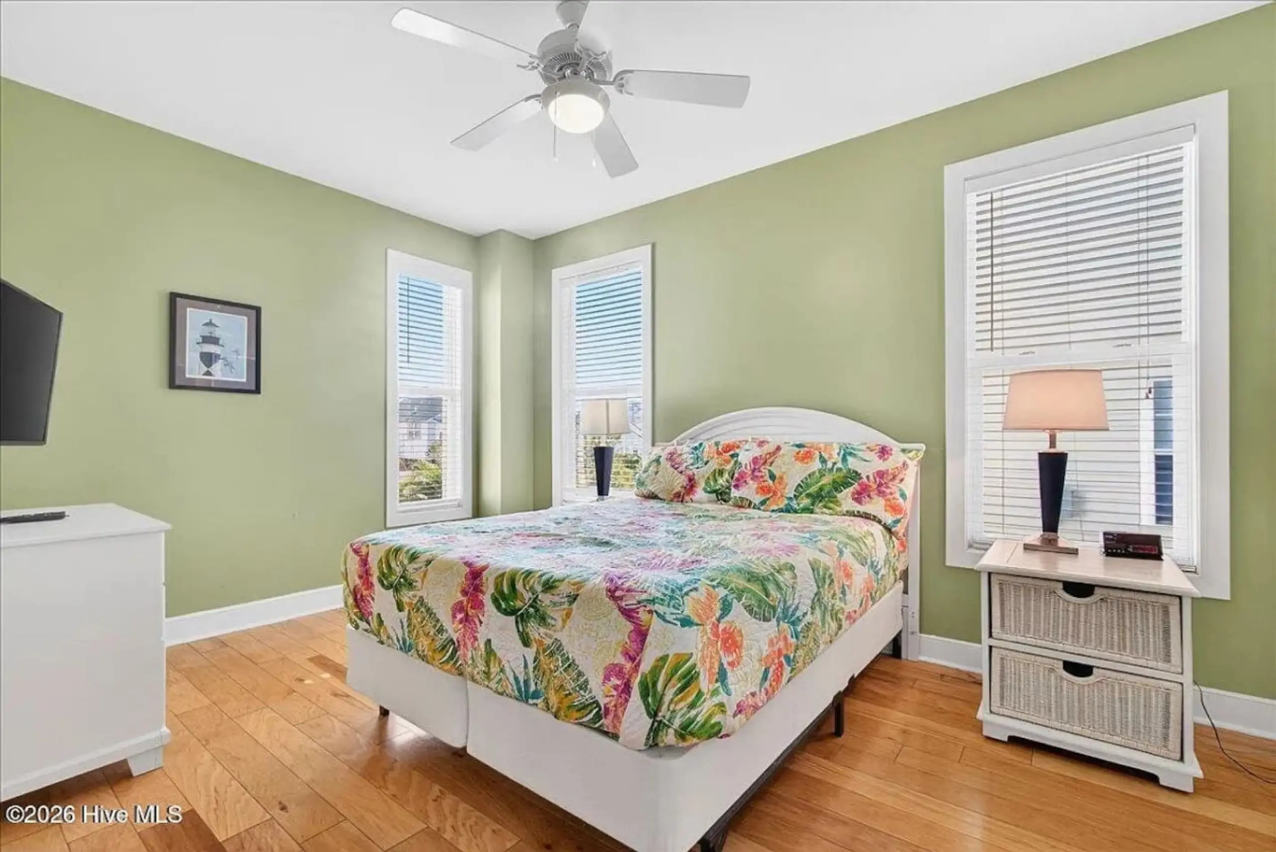 Bright bedroom with floral bedspread and fan