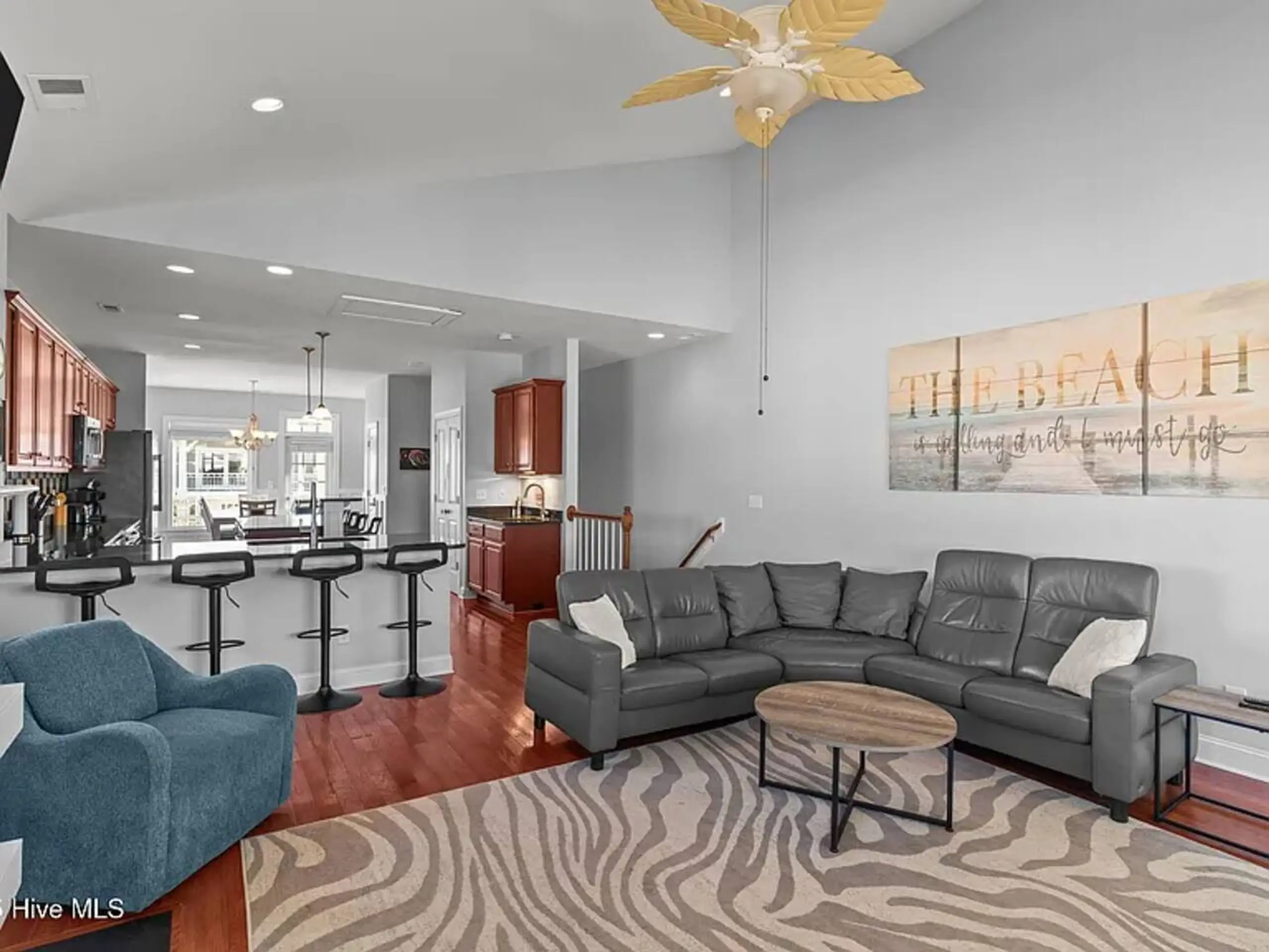Open-plan living room with gray sectional and kitchen